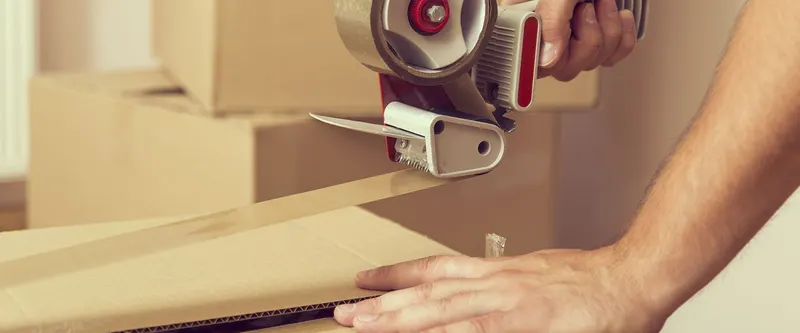 Hands taping a moving box
